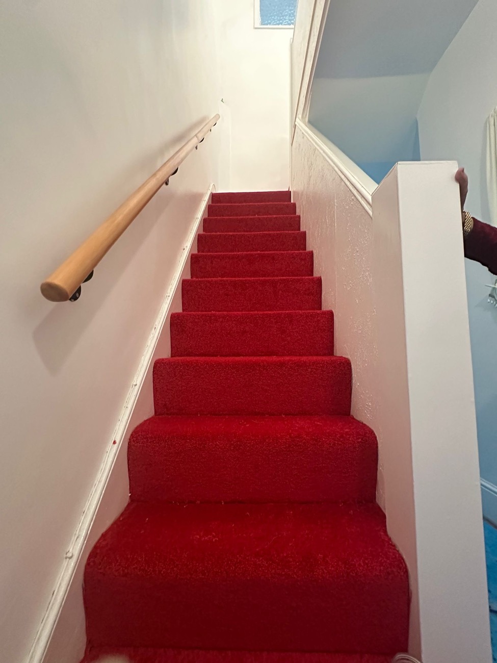 A rich red stair carpet fitted the full width of a staircase in a bright hallway.